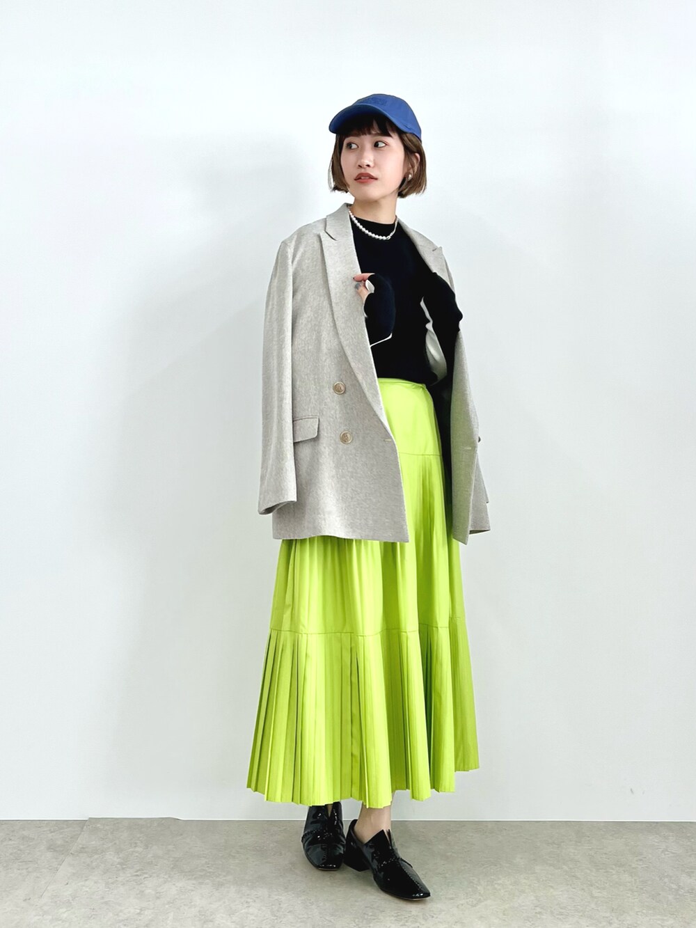 ベージュ系のテーラードジャケット、ブラック系のニット/セーター、グリーン系のスカートを着用したレディースの春コーディネートの3枚目の写真