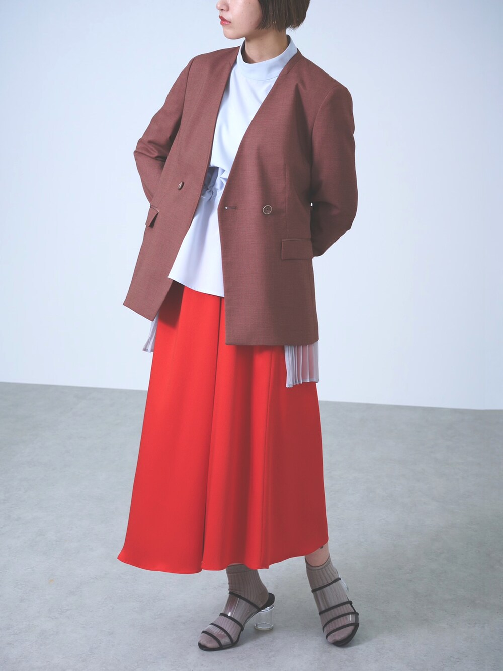 ブラウン系のノーカラージャケット、ブルー系のシャツ/ブラウス、レッド系のスカートを着用したレディースの春コーディネートの2枚目の写真