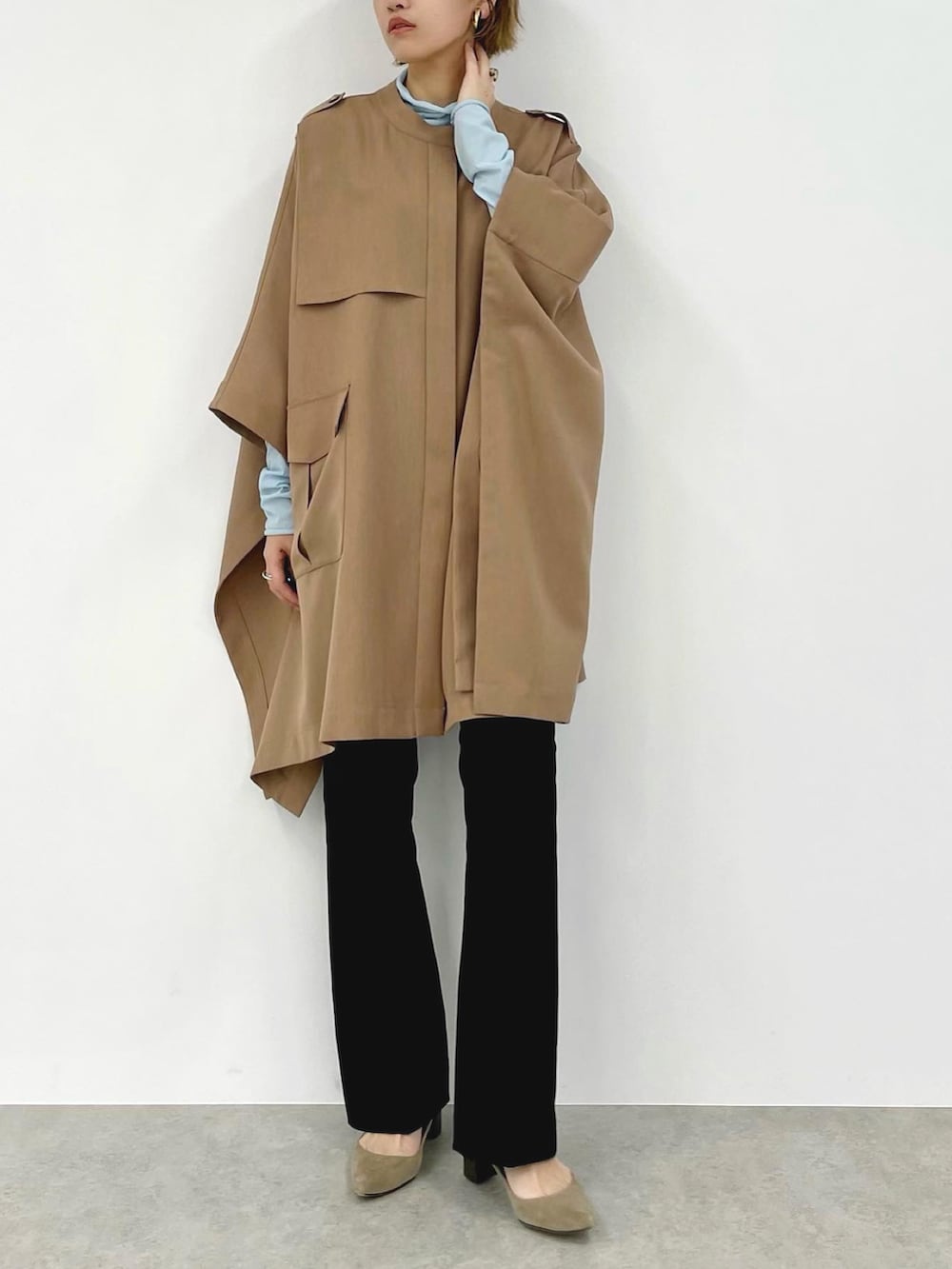 ベージュ系のポンチョ、ブルー系のその他トップス、ブラック系のその他パンツを着用したレディースの春コーディネートの3枚目の写真