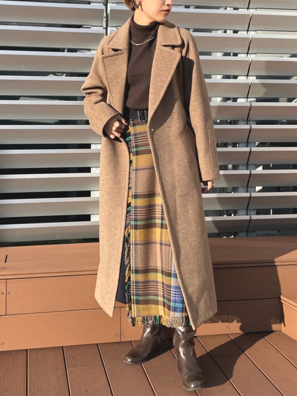 ブラウン系のニット/セーター、ブルー系のスカート、ブラウン系のチェスターコートを着用したレディースの春コーディネートの3枚目の写真