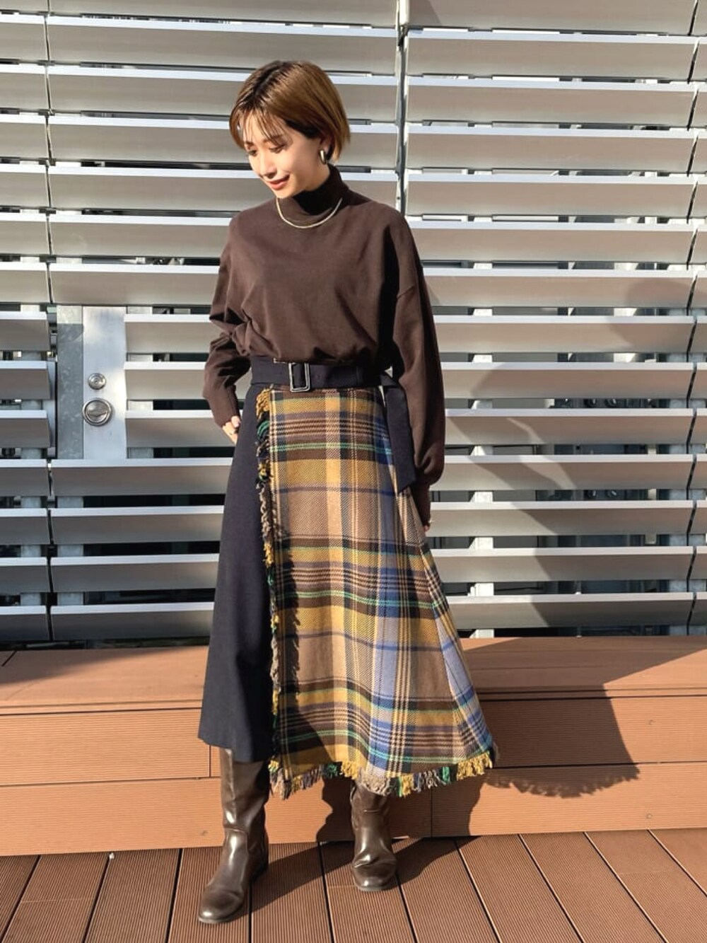 ブラウン系のチェスターコート、ブラウン系のニット/セーター、ブルー系のスカートを着用したレディースの春コーディネートの3枚目の写真