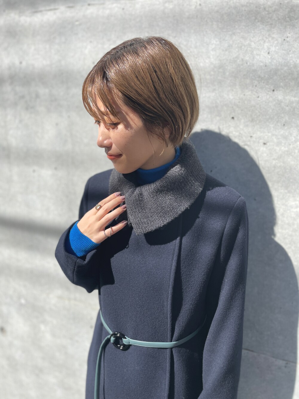 ブルー系のチェスターコート、グレー系のニット/セーター、ブラック系のショルダーバッグを着用したレディースの春コーディネートの4枚目の写真