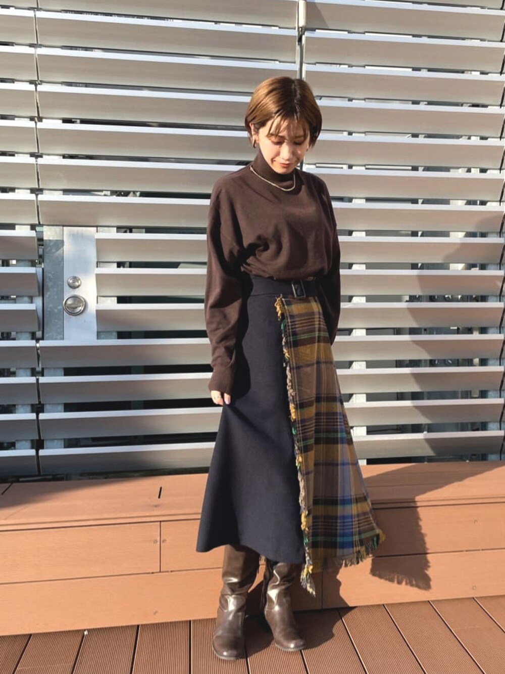 ブラウン系のニット/セーター、ブルー系のスカート、ブラウン系のチェスターコートを着用したレディースの春コーディネートの2枚目の写真