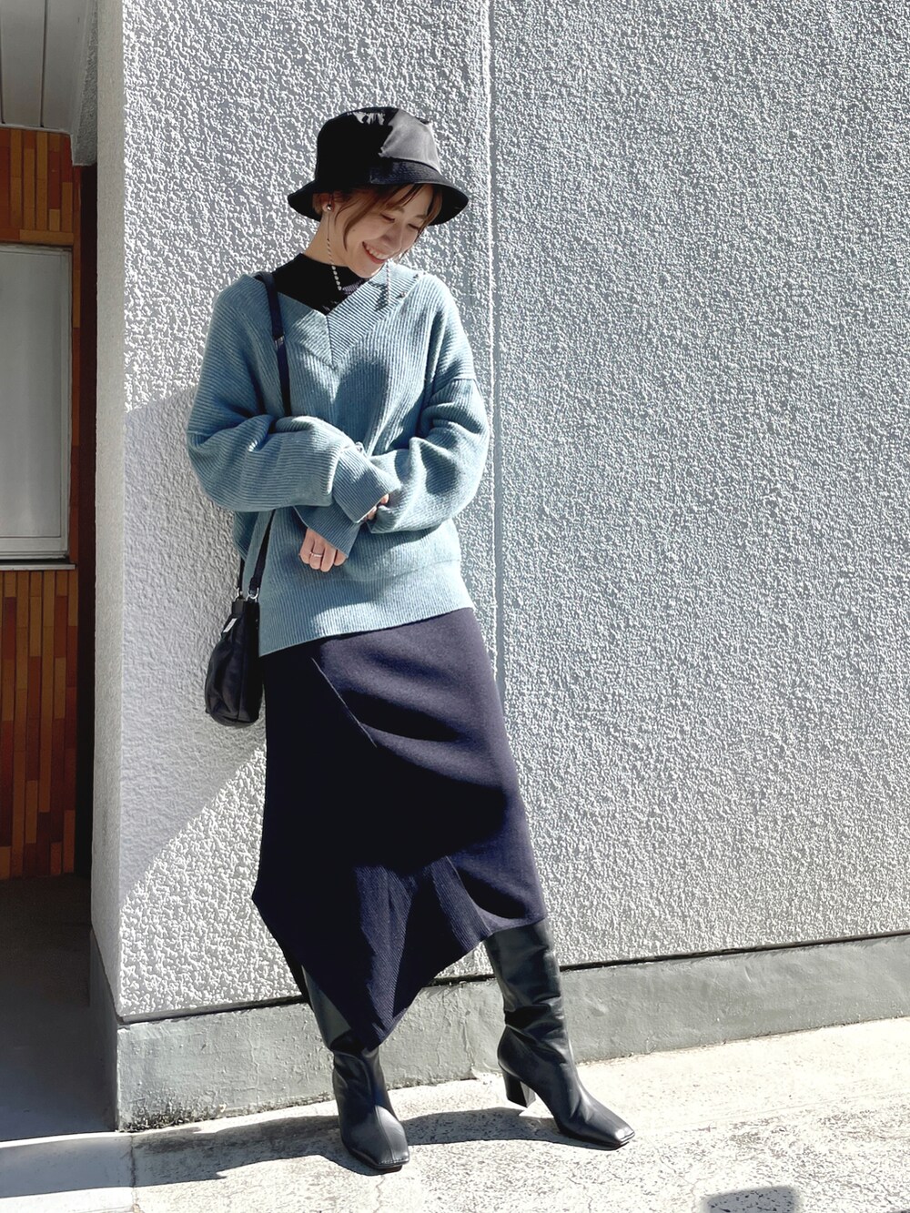 ブラック系のダウンジャケット/コート、ブルー系のニット/セーター、ブルー系のワンピースを着用したレディースの春コーディネートの3枚目の写真
