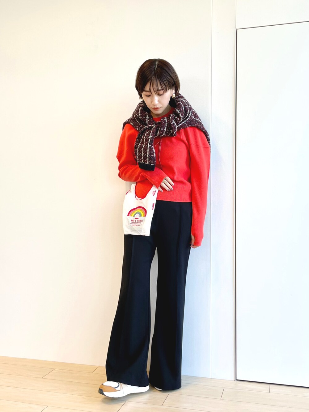 オレンジ系のニット/セーター、ブラック系のその他パンツを着用したレディースの冬コーディネートの2枚目の写真