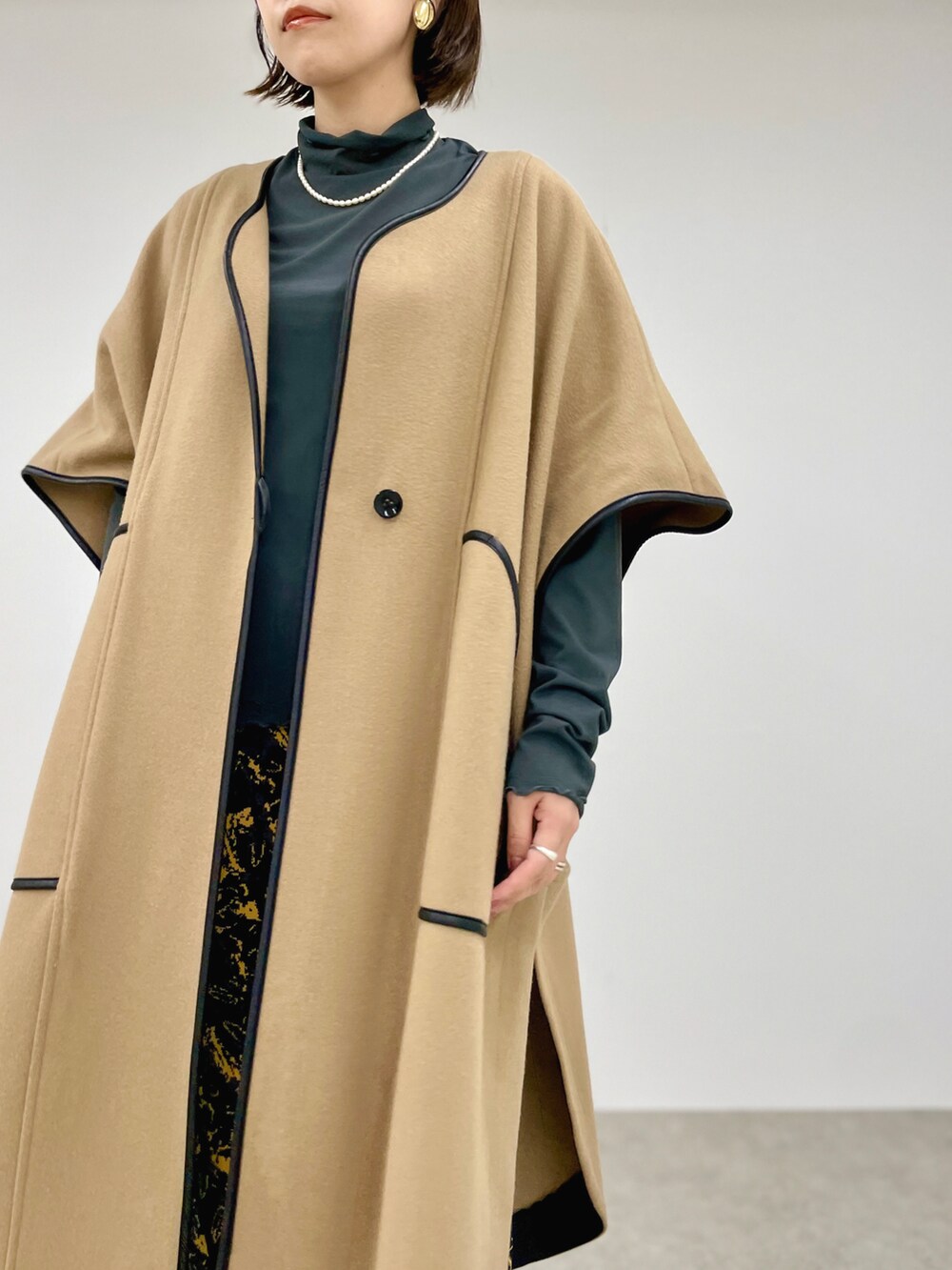 ベージュ系のその他アウター、グリーン系のTシャツ/カットソー、ブラック系のスカートを着用したレディースの秋コーディネートの2枚目の写真