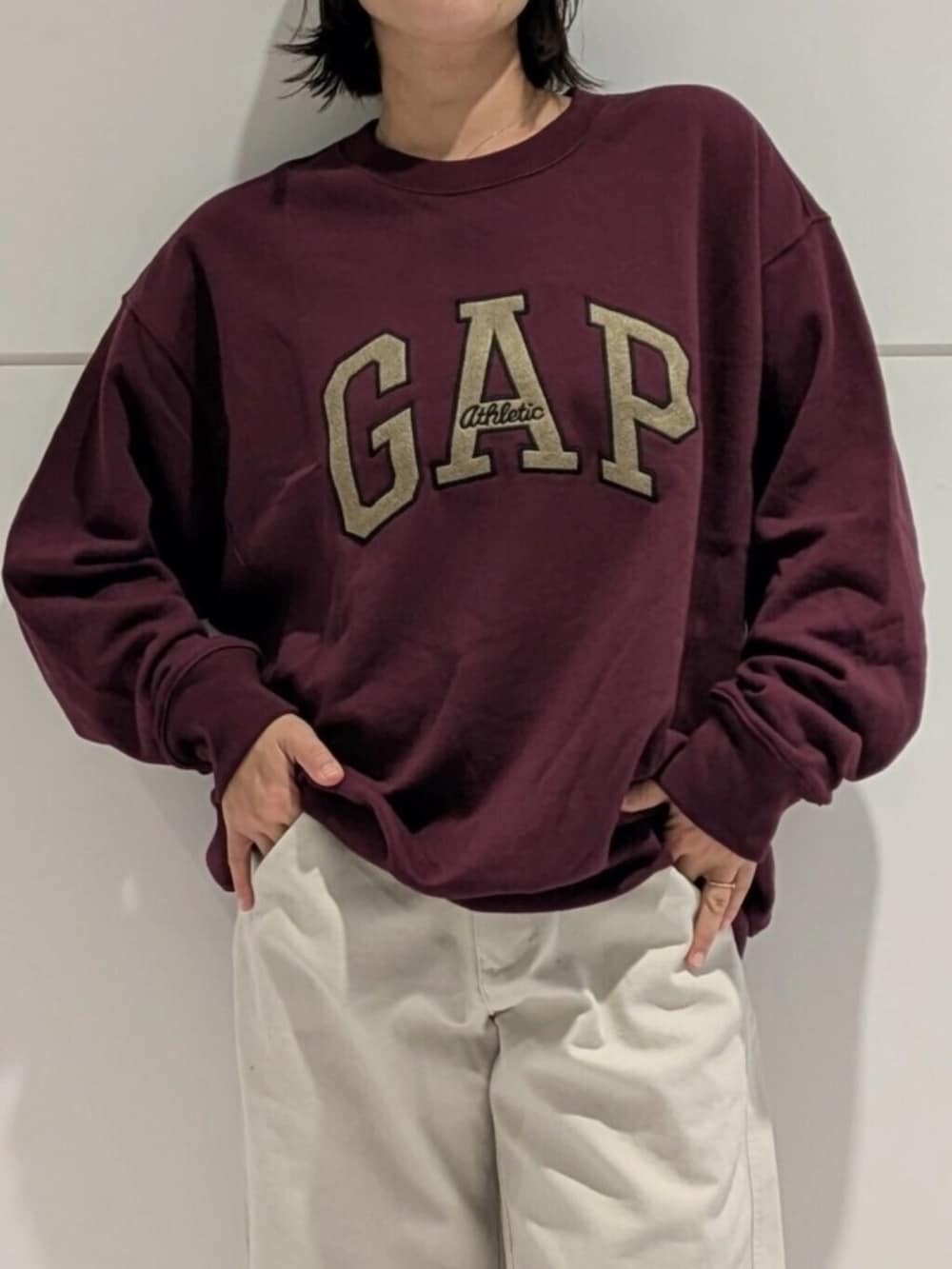 ホワイト系のチノパンツ、レッド系のスウェット、ブルー系のキャップを着用したレディースの秋コーディネートの3枚目の写真