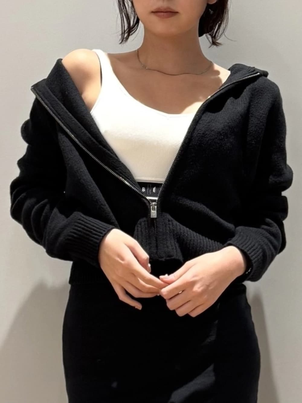 ブラック系のスカート、ブラック系のニット/セーター、ホワイト系のスポーツブラを着用したレディースの秋コーディネートの3枚目の写真