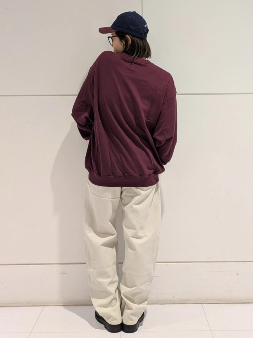 ホワイト系のチノパンツ、レッド系のスウェット、ブルー系のキャップを着用したレディースの秋コーディネートの2枚目の写真