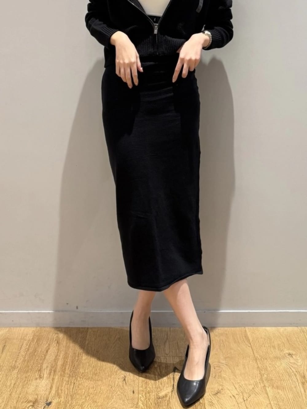 ブラック系のスカート、ブラック系のニット/セーター、ホワイト系のスポーツブラを着用したレディースの秋コーディネートの4枚目の写真