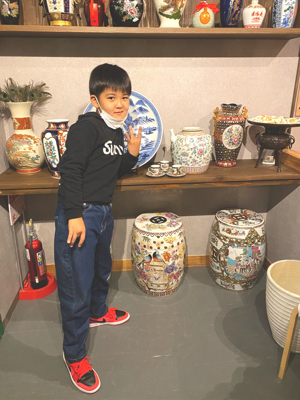 ブルー系のデニムパンツ、ブラック系のパーカー、レッド系のスニーカーを着用したキッズの秋コーディネートの2枚目の写真