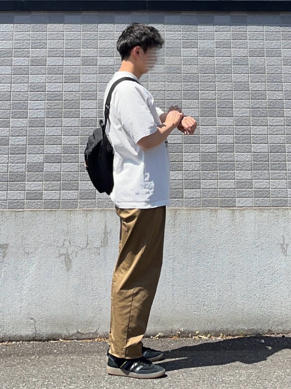 ブラック系のスニーカー、ベージュ系のチノパンツ、ホワイト系のTシャツ/カットソーを着用したメンズの春コーディネートの2枚目の写真