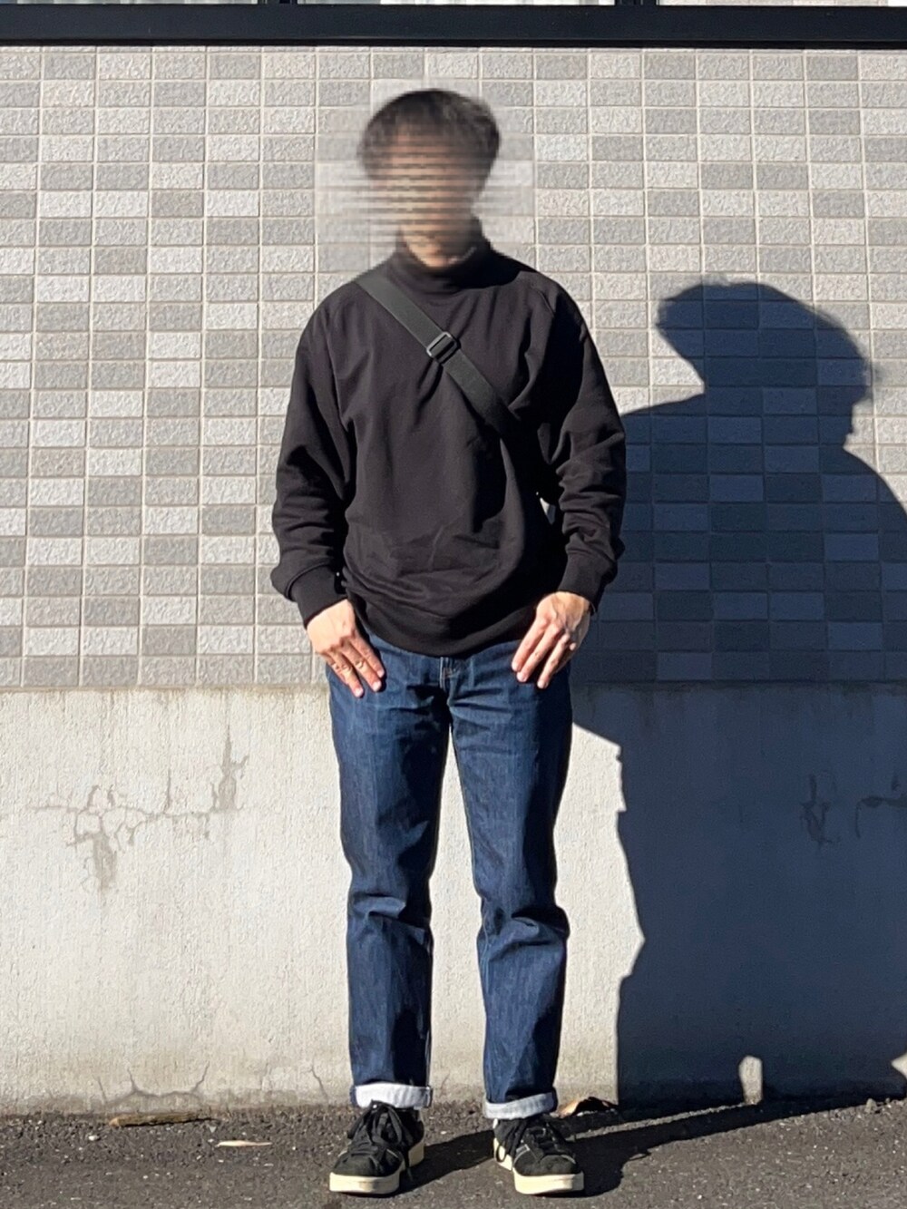 ブラック系のスニーカー、ブルー系のデニムパンツ、ブラック系のスウェットを着用したメンズの秋コーディネートの2枚目の写真