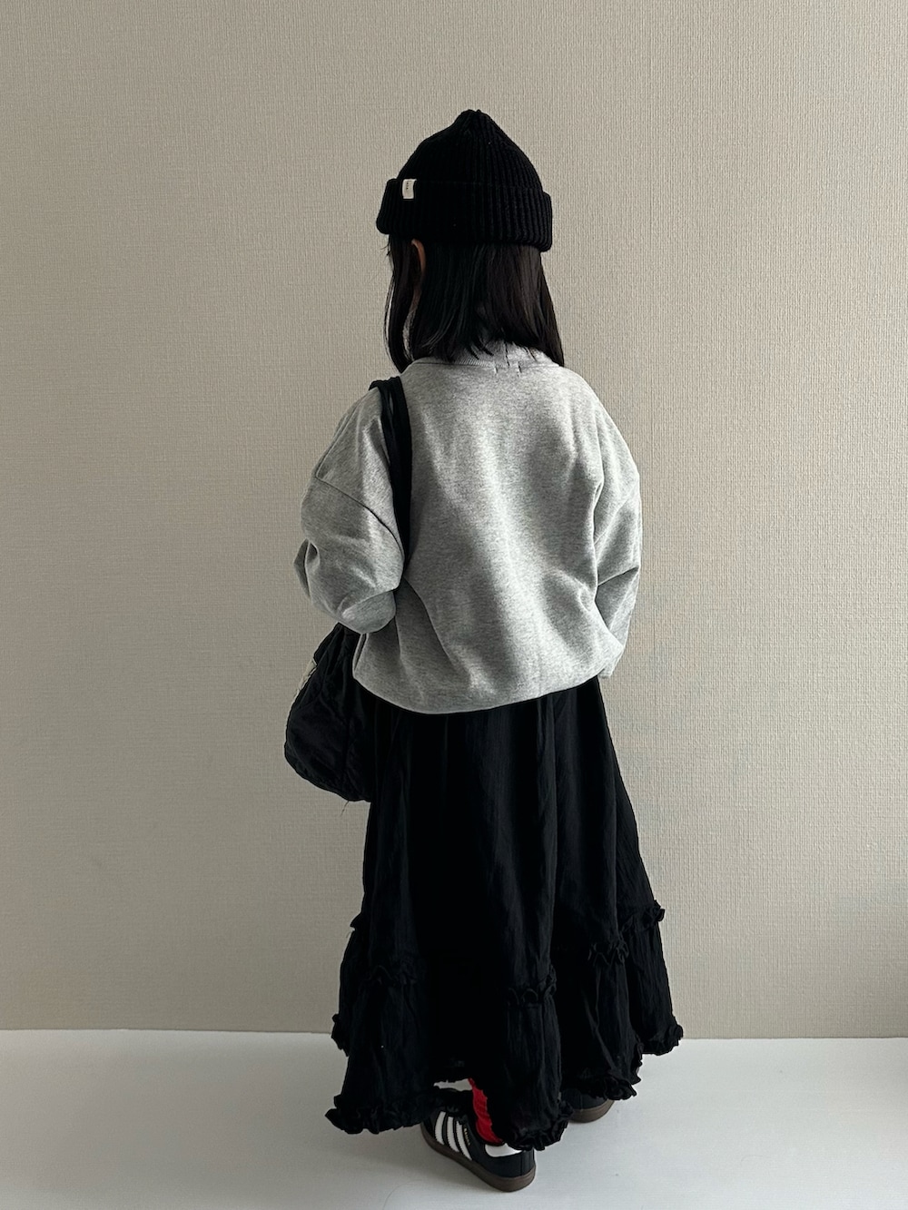 グレー系のスウェット、ブラック系のスカート、ブラック系のショルダーバッグを着用したキッズの冬コーディネートの3枚目の写真