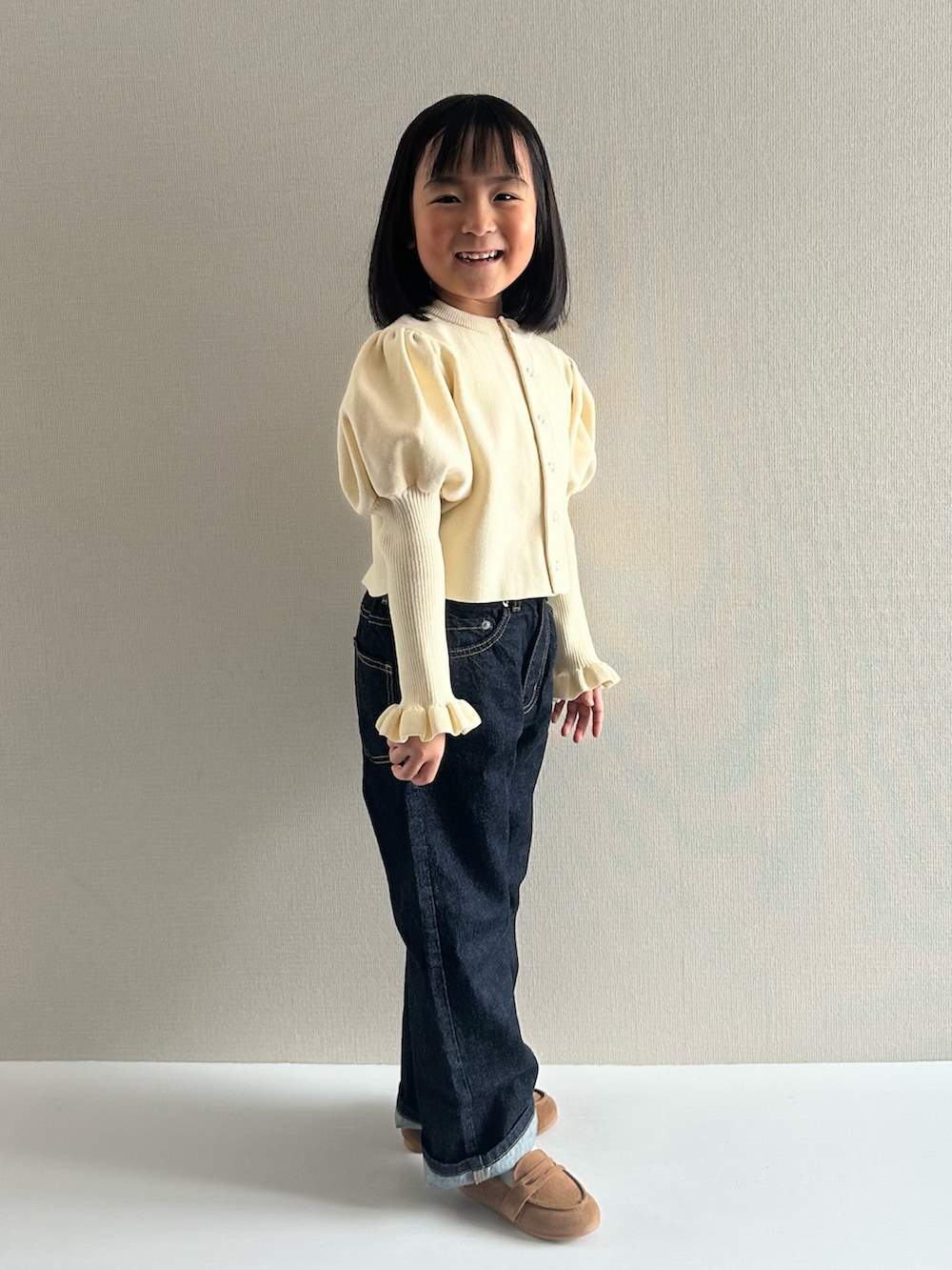 ホワイト系のカーディガン/ボレロ、ブルー系のデニムパンツ、ブラウン系のローファーを着用したキッズの冬コーディネートの2枚目の写真