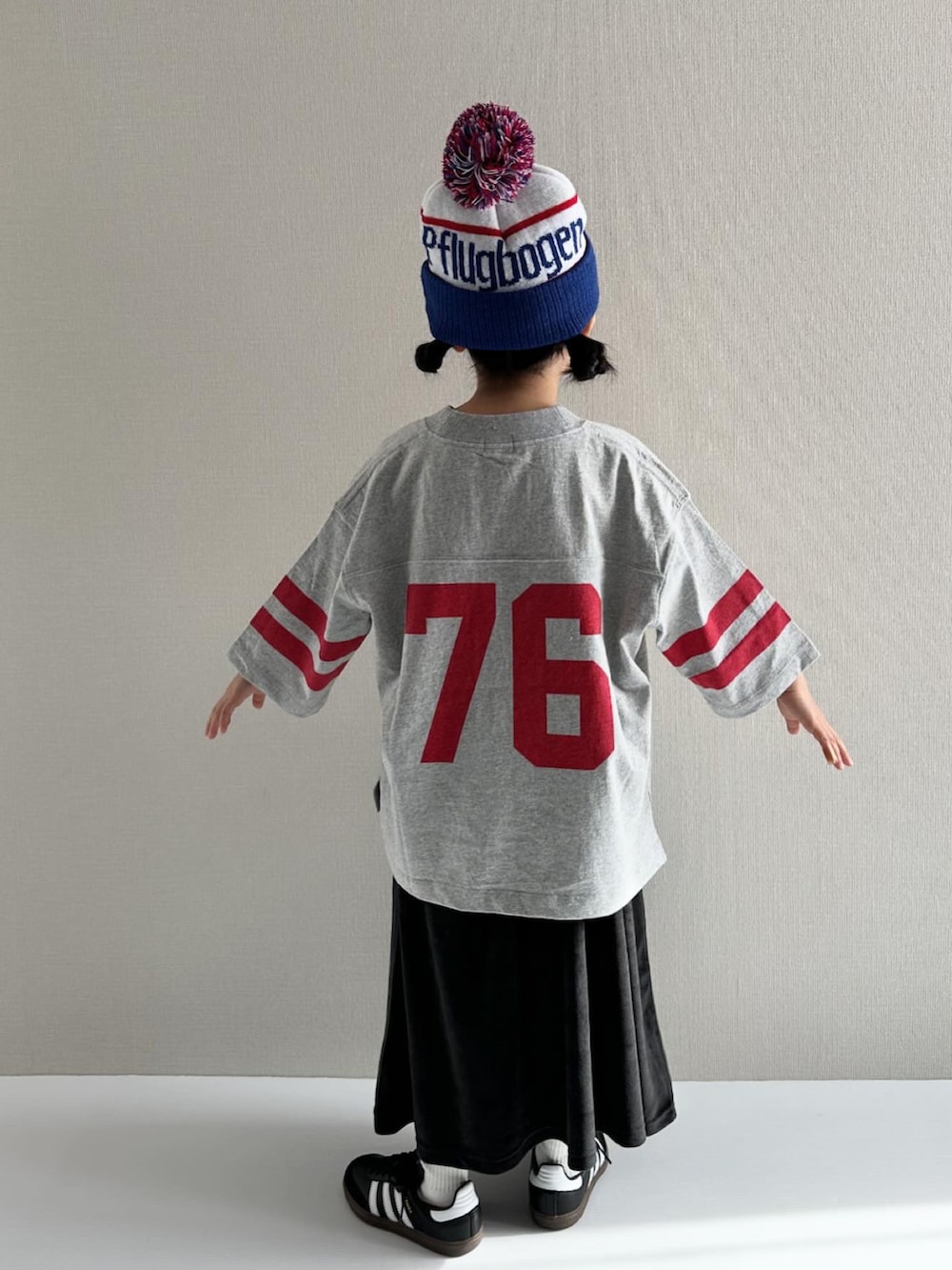 グレー系のTシャツ/カットソー、ブラック系のスカート、ブラック系のスニーカーを着用したキッズの冬コーディネートの3枚目の写真