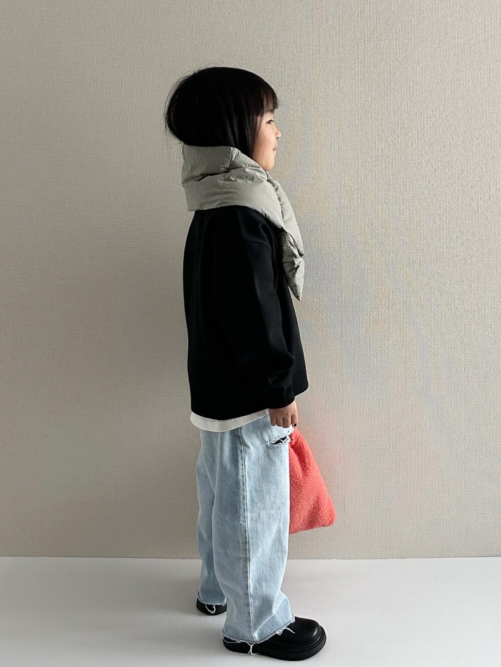 ブラック系のニット/セーター、ブルー系のデニムパンツ、オレンジ系のショルダーバッグを着用したキッズの秋コーディネートの5枚目の写真