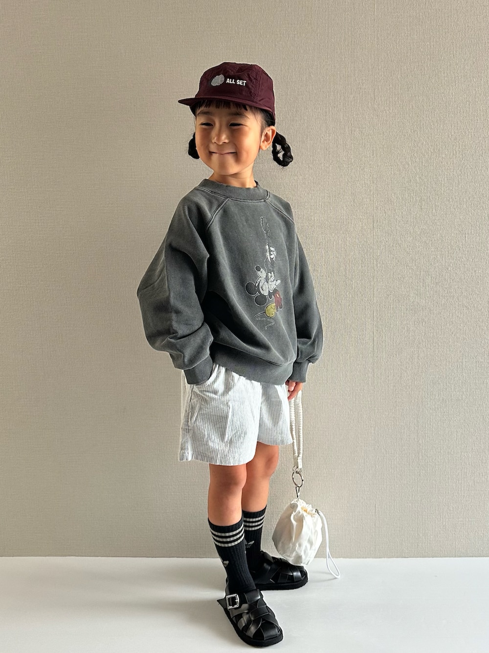 グレー系のスウェット、ブルー系のパンツ、ホワイト系のショルダーバッグを着用したキッズの秋コーディネートの4枚目の写真