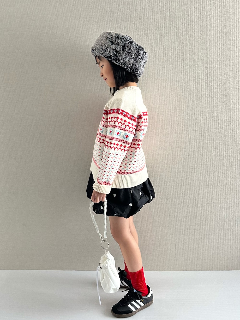 ホワイト系のニット/セーター、ブラック系のスカート、ホワイト系のショルダーバッグを着用したキッズの冬コーディネートの4枚目の写真