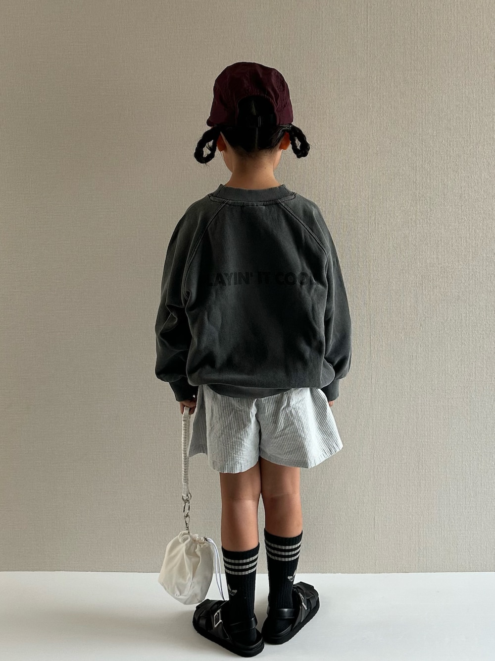 グレー系のスウェット、ブルー系のパンツ、ホワイト系のショルダーバッグを着用したキッズの秋コーディネートの3枚目の写真