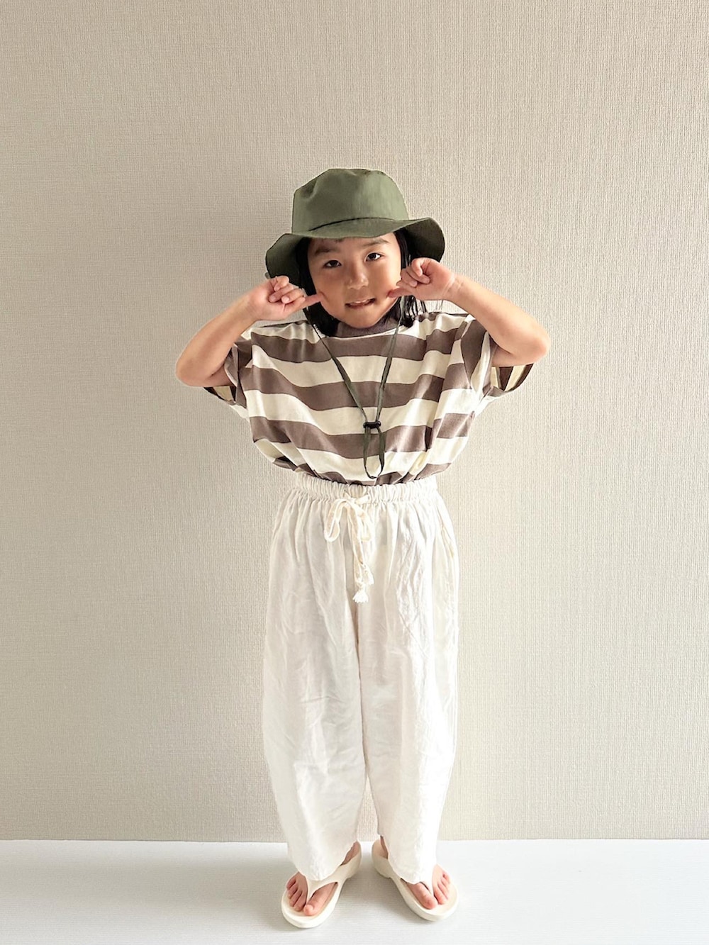 ブラウン系のTシャツ/カットソー、ホワイト系のパンツ、ホワイト系のサンダルを着用したキッズの夏コーディネートの5枚目の写真