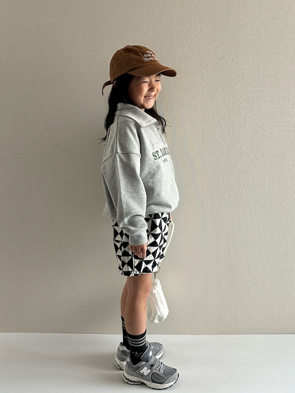 グレー系のスウェット、グレー系のその他パンツ、ホワイト系のショルダーバッグを着用したキッズの秋コーディネートの2枚目の写真