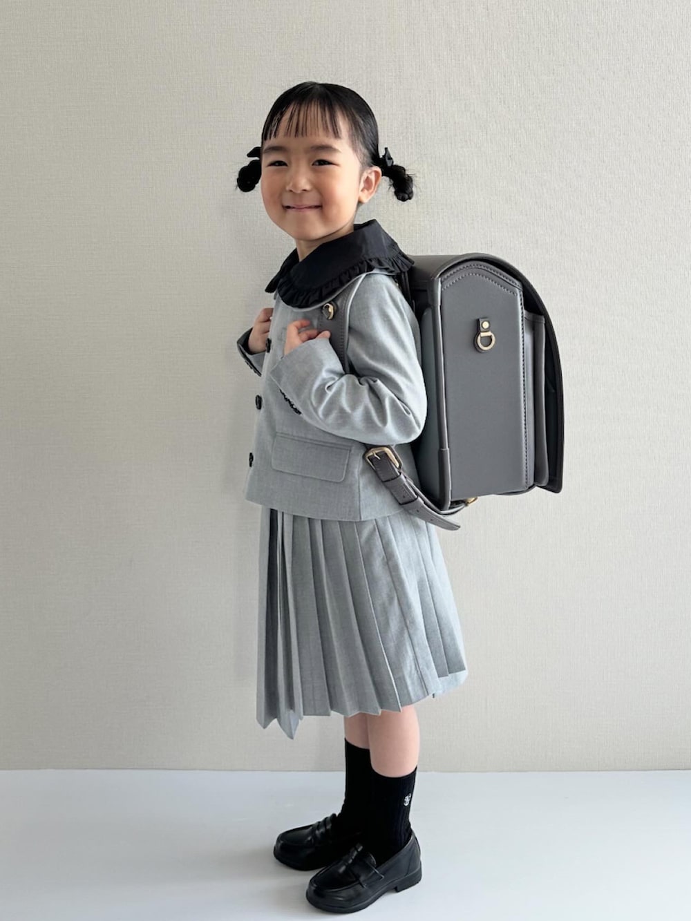 ブラック系のシャツ/ブラウス、グレー系のスーツジャケット、グレー系のスカートを着用したキッズの春コーディネートの2枚目の写真