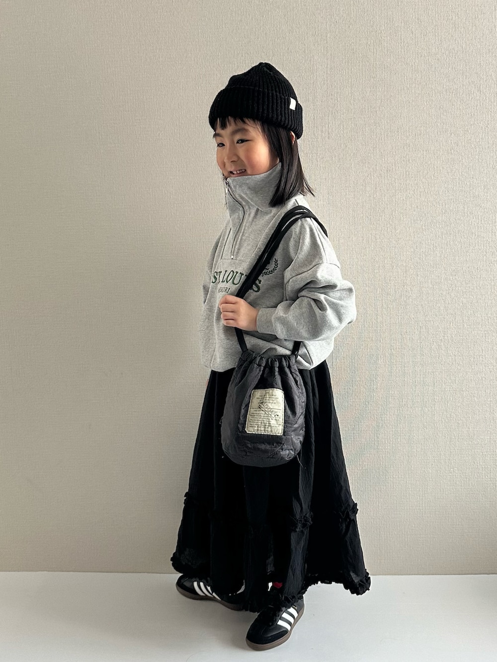 グレー系のスウェット、ブラック系のスカート、ブラック系のショルダーバッグを着用したキッズの冬コーディネートの2枚目の写真