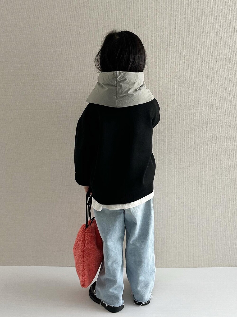 ブラック系のニット/セーター、ブルー系のデニムパンツ、オレンジ系のショルダーバッグを着用したキッズの秋コーディネートの3枚目の写真