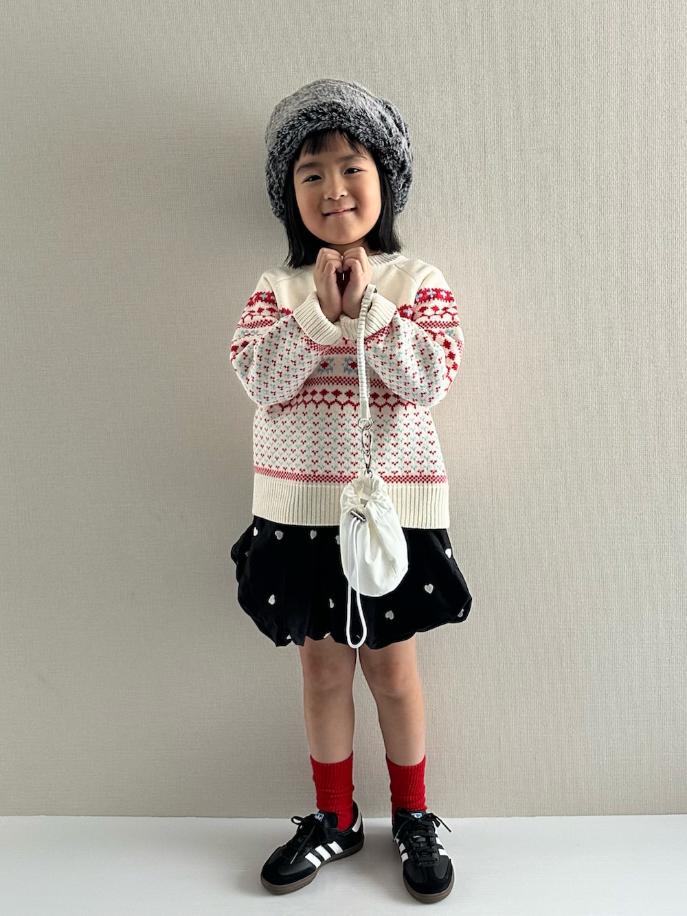 ホワイト系のニット/セーター、ブラック系のスカート、ホワイト系のショルダーバッグを着用したキッズの冬コーディネートの5枚目の写真