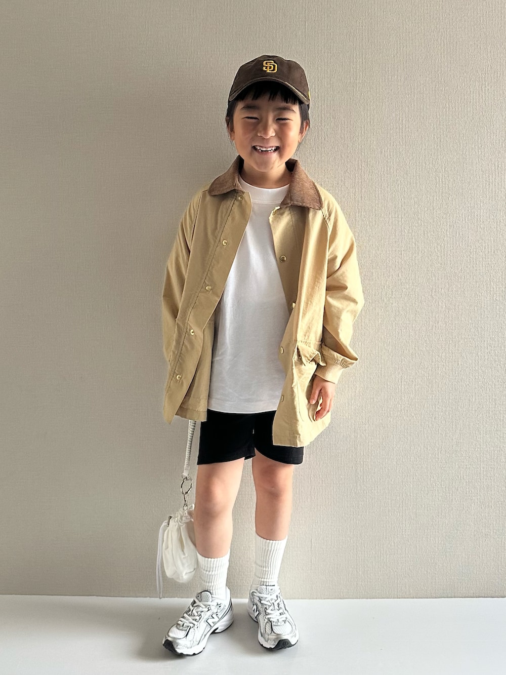 ベージュ系のナイロンジャケット、ホワイト系のTシャツ/カットソー、ブラック系のその他パンツを着用したキッズの春コーディネートの5枚目の写真