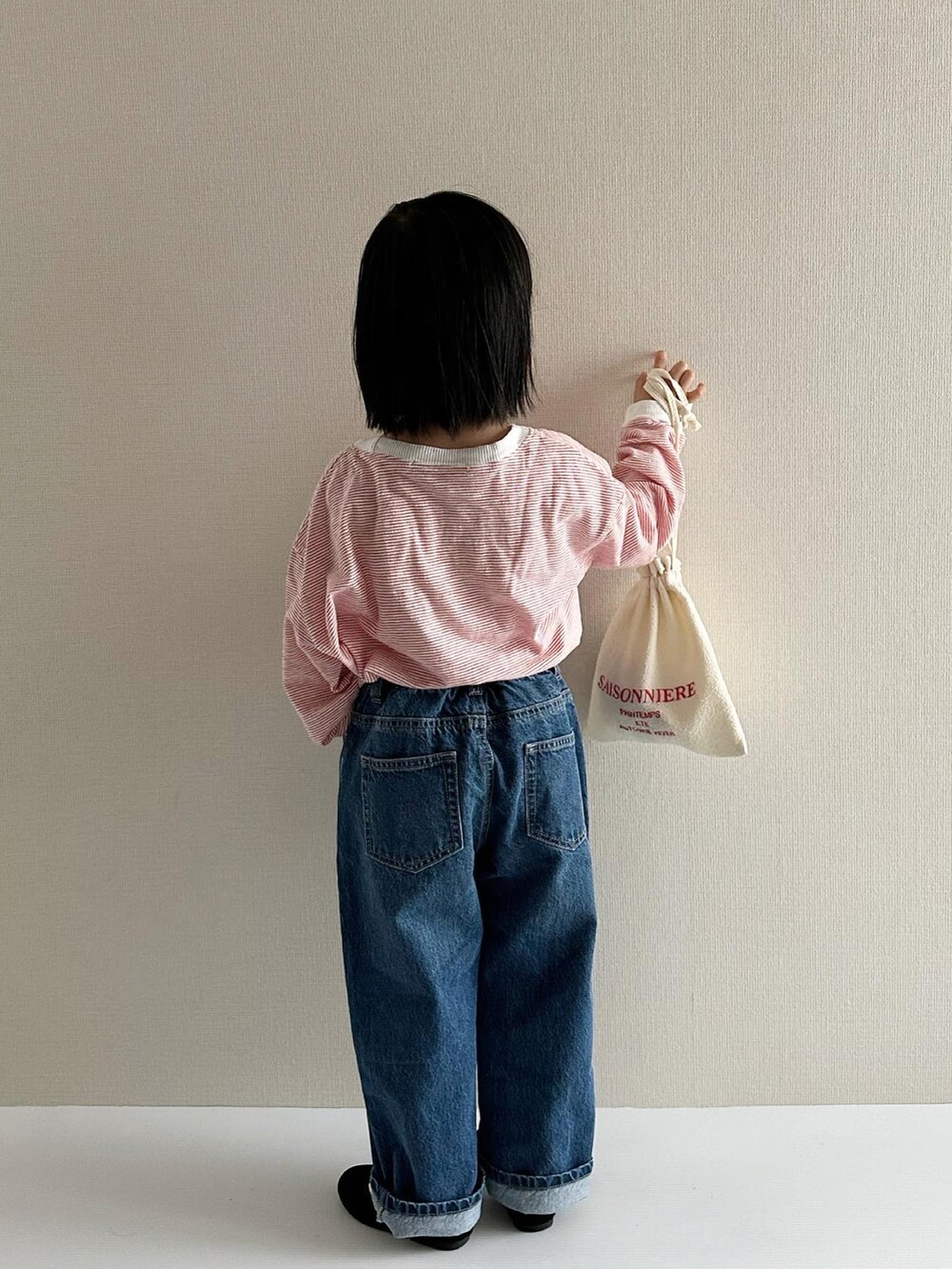 レッド系のトップス、ブルー系のデニムパンツ、ブラック系のその他シューズを着用したキッズの春コーディネートの2枚目の写真