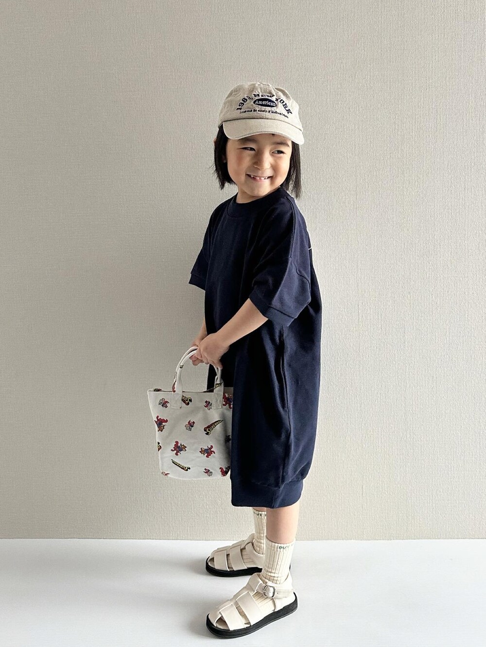 ブルー系のワンピース、ホワイト系のサンダル、その他のトートバッグを着用したキッズの春コーディネートの2枚目の写真