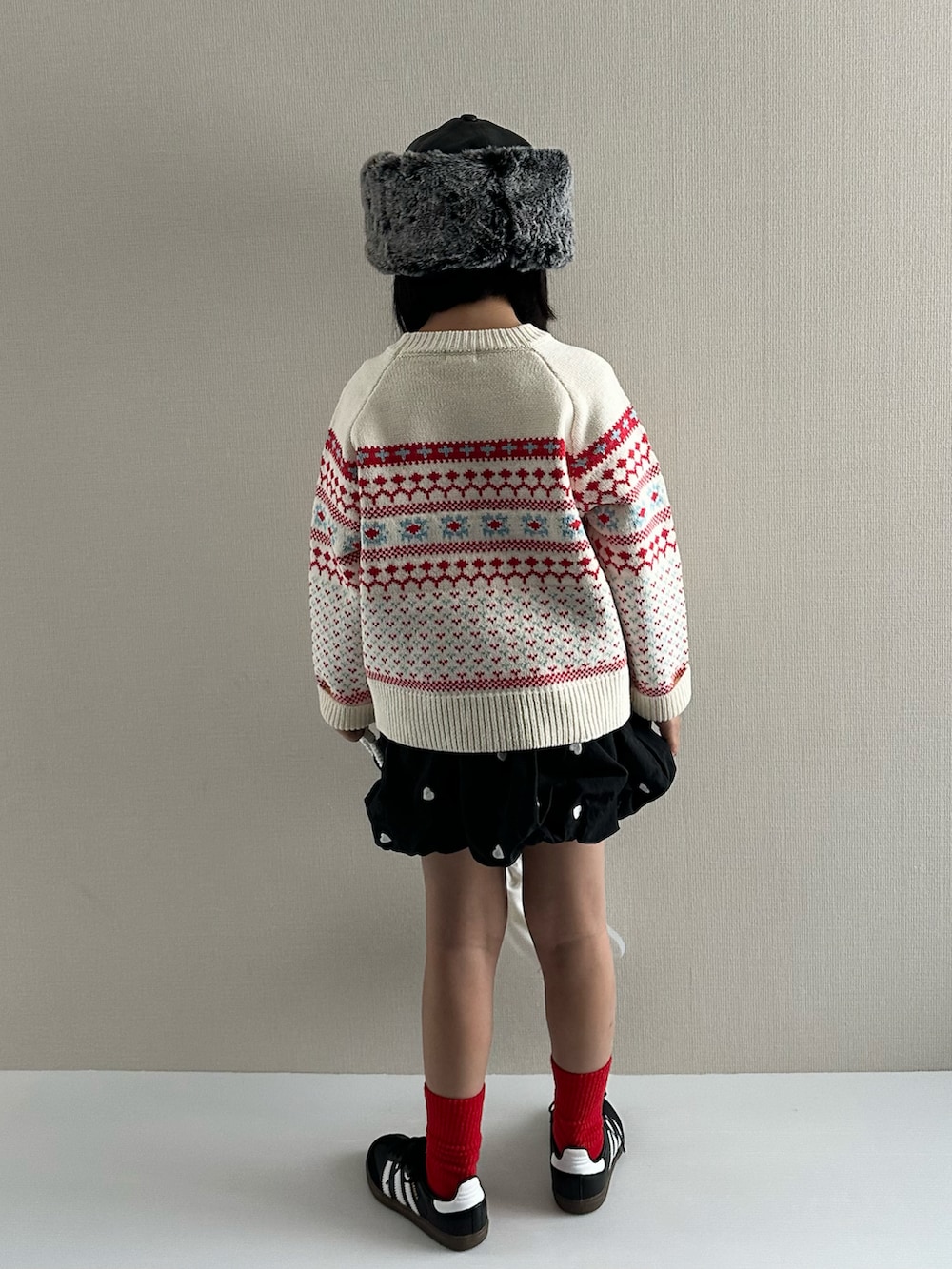 ホワイト系のニット/セーター、ブラック系のスカート、ホワイト系のショルダーバッグを着用したキッズの冬コーディネートの3枚目の写真