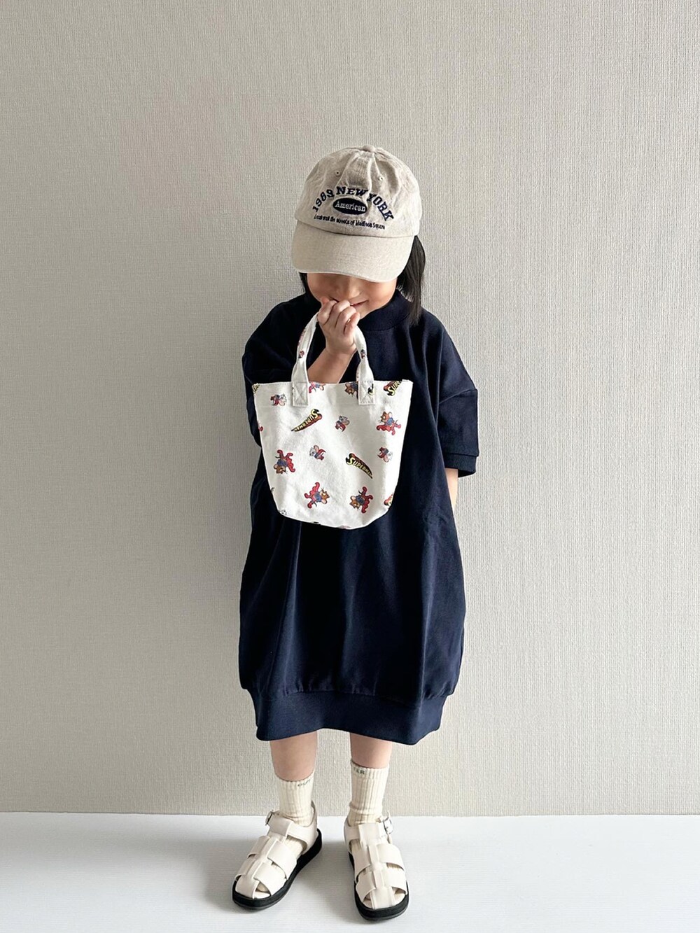 ブルー系のワンピース、ホワイト系のサンダル、その他のトートバッグを着用したキッズの春コーディネートの3枚目の写真