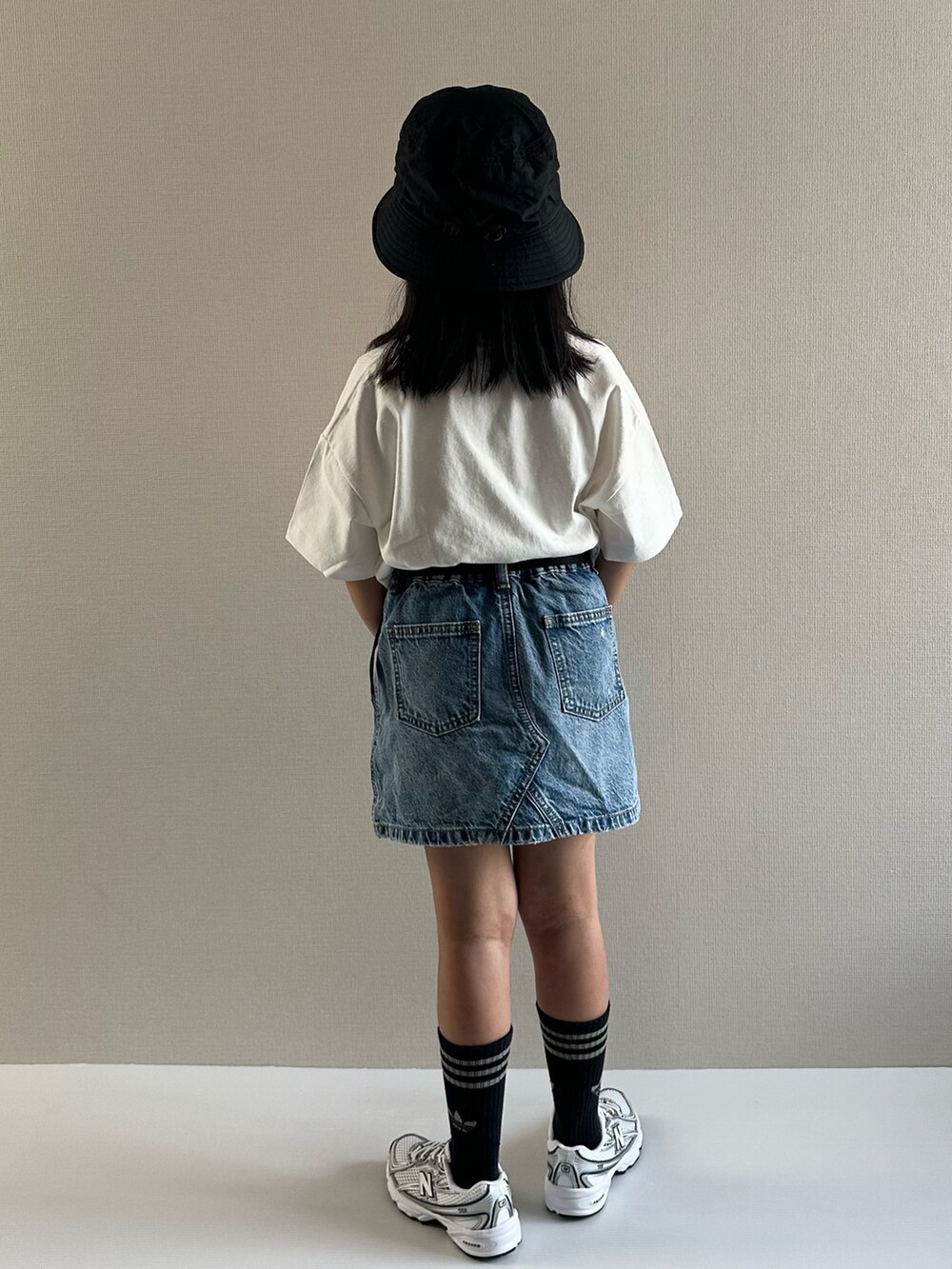 ホワイト系のTシャツ/カットソー、ブルー系のデニムスカート、ホワイト系のスニーカーを着用したキッズの夏コーディネートの3枚目の写真