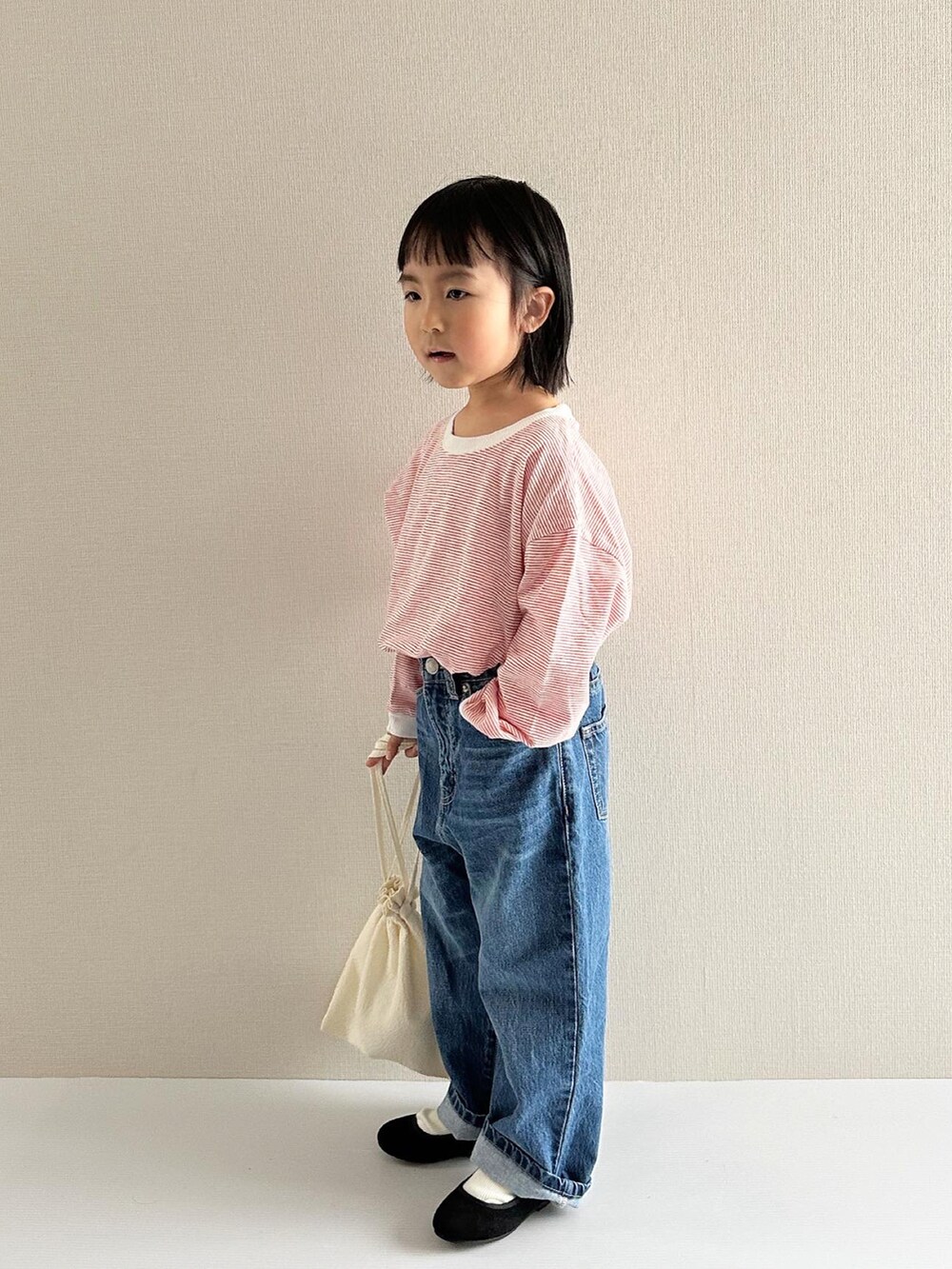 レッド系のトップス、ブルー系のデニムパンツ、ブラック系のその他シューズを着用したキッズの春コーディネートの4枚目の写真