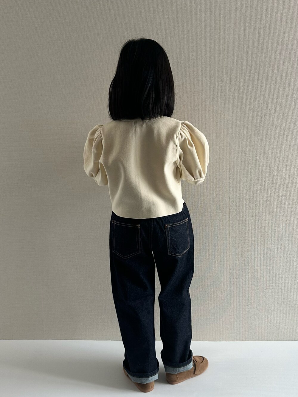 ホワイト系のカーディガン/ボレロ、ブルー系のデニムパンツ、ブラウン系のローファーを着用したキッズの冬コーディネートの3枚目の写真