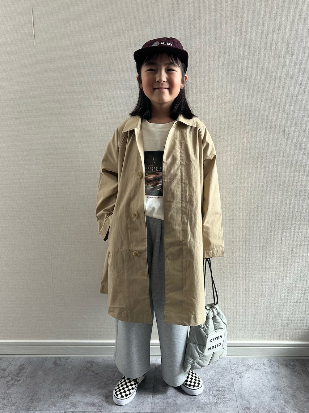 ベージュ系のステンカラーコート、ベージュ系のTシャツ/カットソー、グレー系のスウェットパンツを着用したキッズの春コーディネートの5枚目の写真