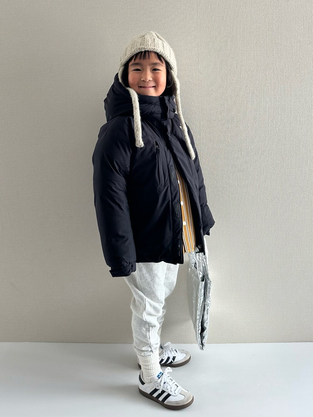 ブラック系のダウンジャケット/コート、イエロー系のシャツ/ブラウス、グレー系のスウェットパンツを着用したキッズの冬コーディネートの2枚目の写真