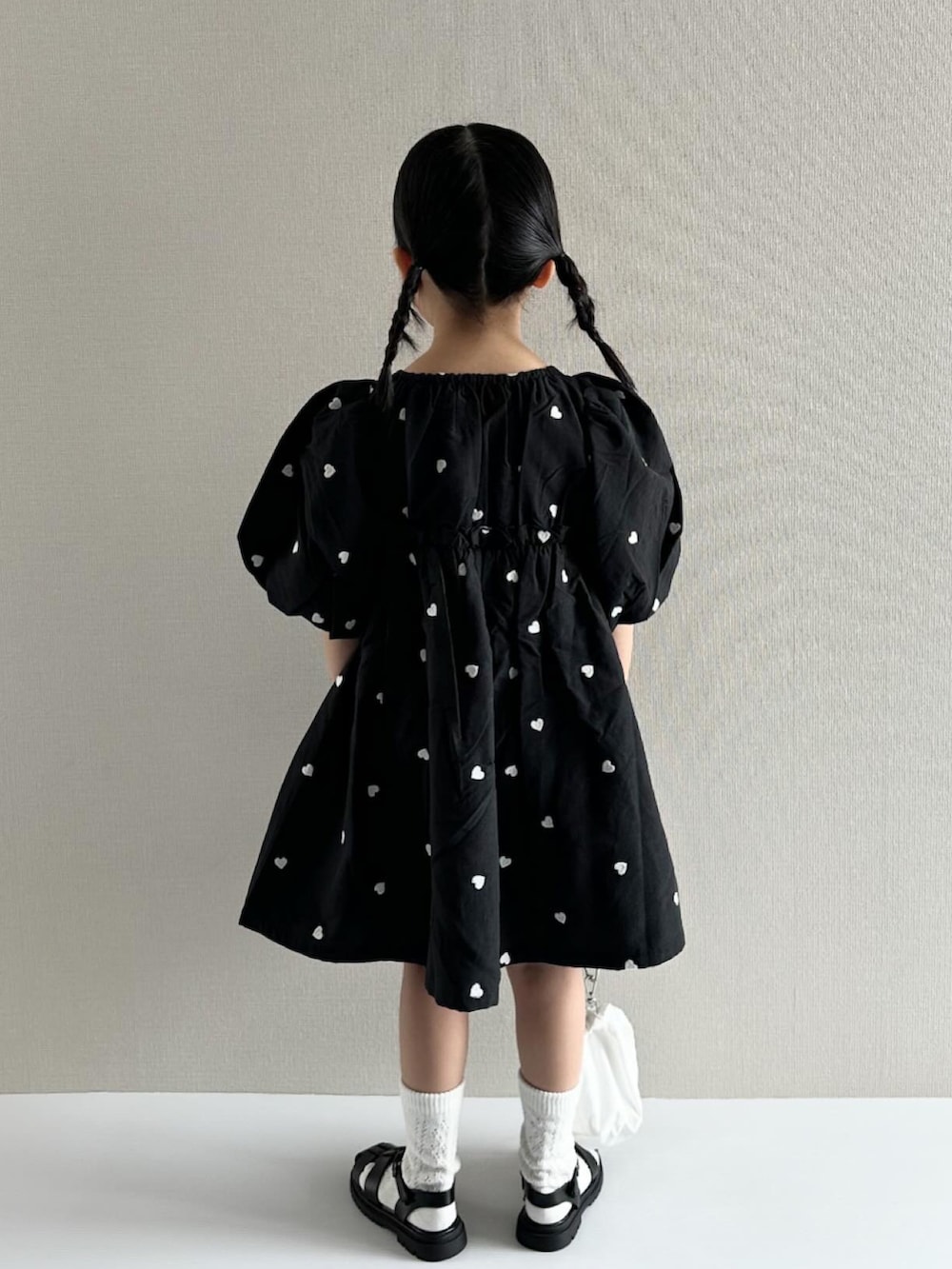 ブラック系のワンピース、ホワイト系のショルダーバッグ、ブラック系のサンダルを着用したキッズの春コーディネートの5枚目の写真