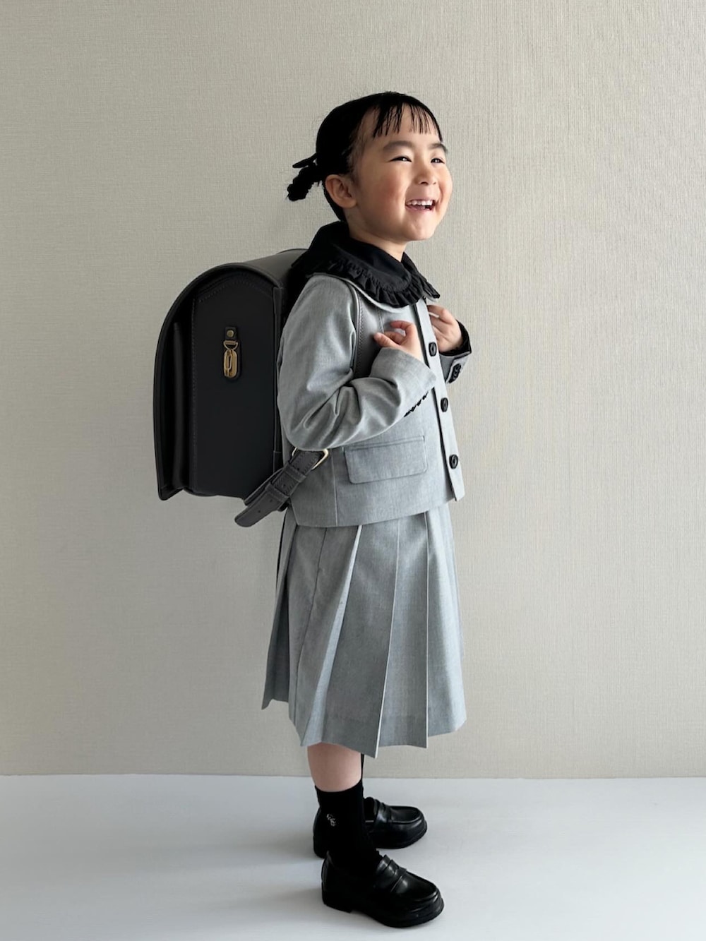 ブラック系のシャツ/ブラウス、グレー系のスーツジャケット、グレー系のスカートを着用したキッズの春コーディネートの4枚目の写真