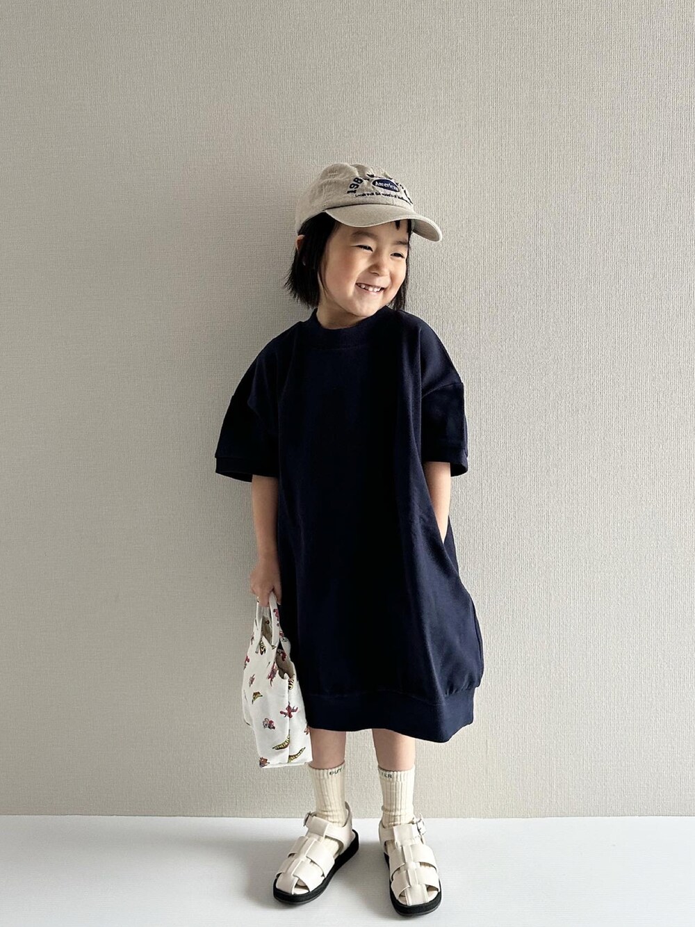 ブルー系のワンピース、ホワイト系のサンダル、その他のトートバッグを着用したキッズの春コーディネートの4枚目の写真