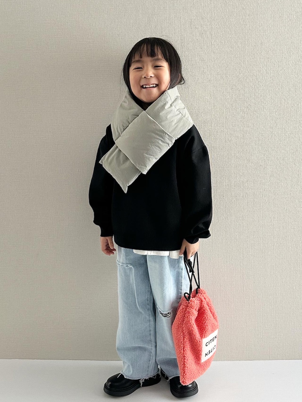 ブラック系のニット/セーター、ブルー系のデニムパンツ、オレンジ系のショルダーバッグを着用したキッズの秋コーディネートの4枚目の写真