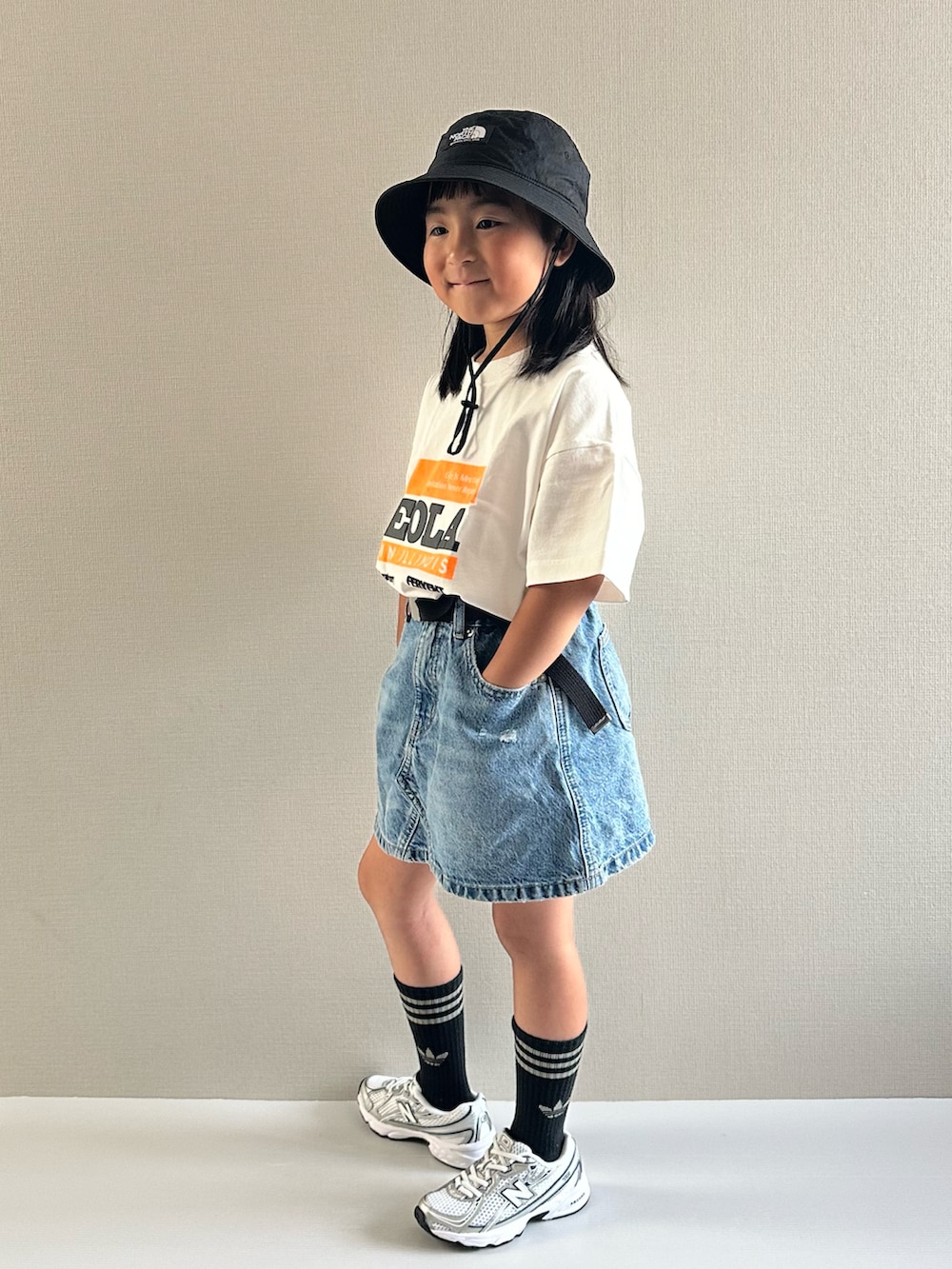 ホワイト系のTシャツ/カットソー、ブルー系のデニムスカート、ホワイト系のスニーカーを着用したキッズの夏コーディネートの4枚目の写真