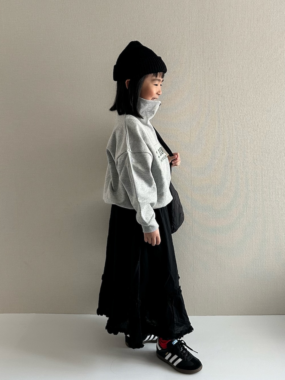 グレー系のスウェット、ブラック系のスカート、ブラック系のショルダーバッグを着用したキッズの冬コーディネートの4枚目の写真