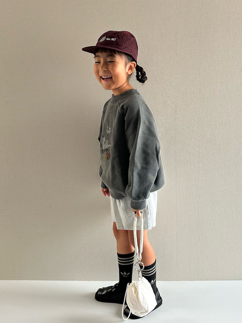 グレー系のスウェット、ブルー系のパンツ、ホワイト系のショルダーバッグを着用したキッズの秋コーディネートの2枚目の写真