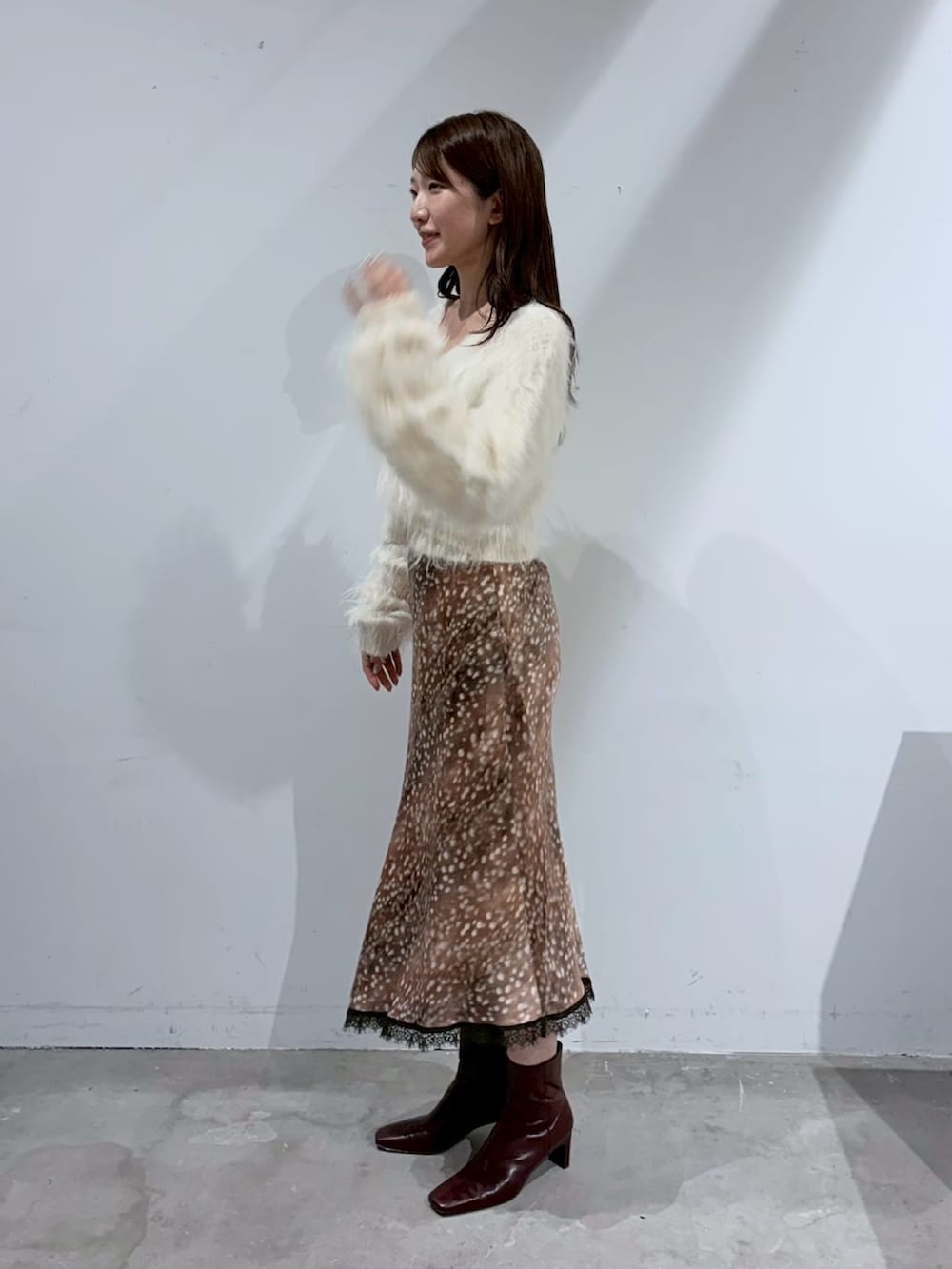 ホワイト系のニット/セーター、ブラウン系のスカート、レッド系のブーツを着用したレディースの夏コーディネートの3枚目の写真