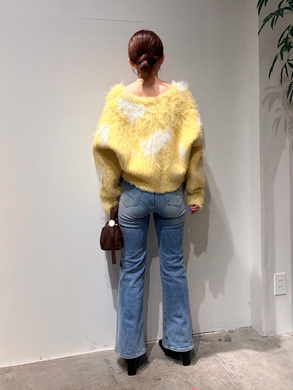 イエロー系のカーディガン/ボレロ、ブルー系のデニムパンツ、ブラック系のブーツを着用したレディースの秋コーディネートの3枚目の写真