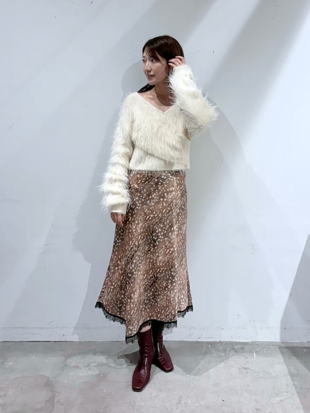 ホワイト系のニット/セーター、ブラウン系のスカート、レッド系のブーツを着用したレディースの夏コーディネートの2枚目の写真